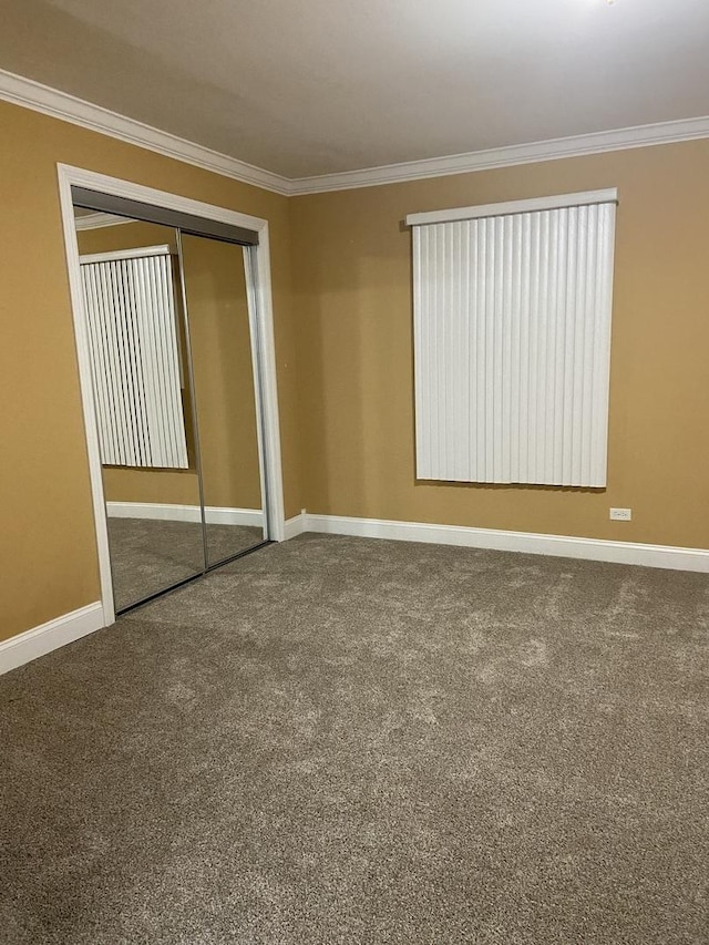 unfurnished bedroom featuring carpet, crown molding, and a closet