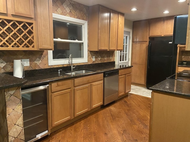 kitchen with sink, beverage cooler, dark hardwood / wood-style flooring, dark stone countertops, and black appliances