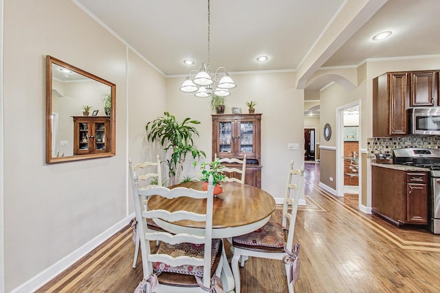 dining space with crown molding, light hardwood / wood-style flooring, and a notable chandelier