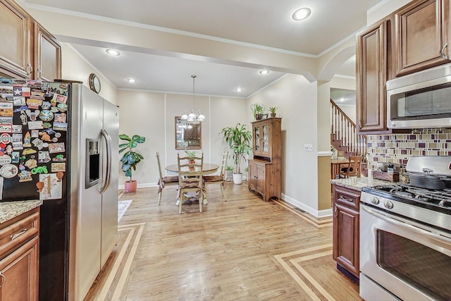 kitchen with backsplash, light hardwood / wood-style flooring, decorative light fixtures, light stone counters, and stainless steel appliances