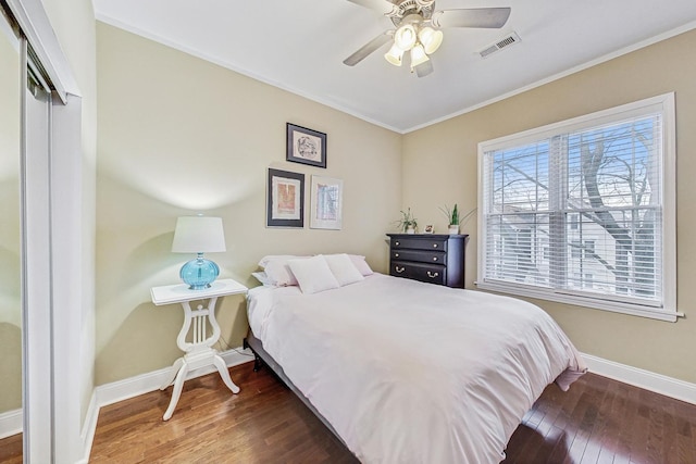 bedroom with a closet, dark hardwood / wood-style floors, ceiling fan, and crown molding