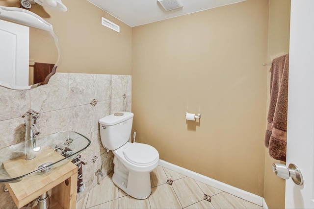 bathroom featuring tile patterned flooring, toilet, and tile walls