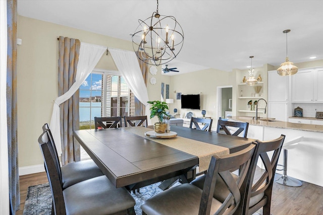 dining space featuring sink, ceiling fan with notable chandelier, and light hardwood / wood-style flooring