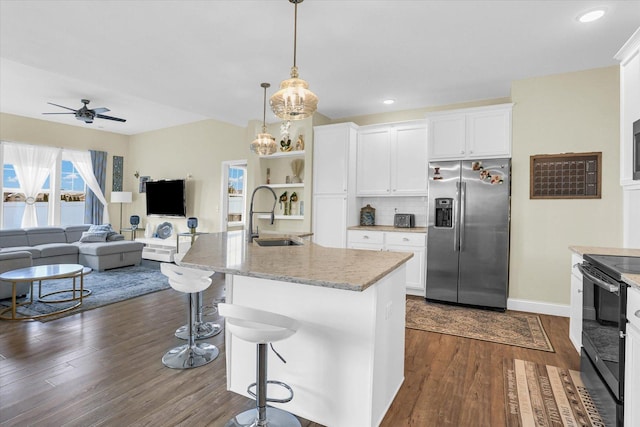 kitchen with sink, stainless steel refrigerator with ice dispenser, a breakfast bar area, a kitchen island with sink, and white cabinets