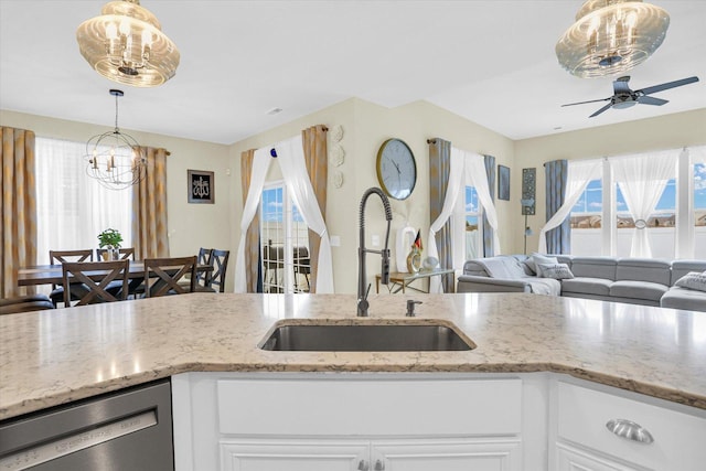 kitchen with stainless steel dishwasher, light stone countertops, white cabinetry, and sink