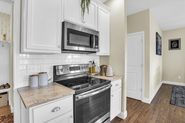 kitchen with white cabinets, dark hardwood / wood-style flooring, backsplash, and stainless steel appliances