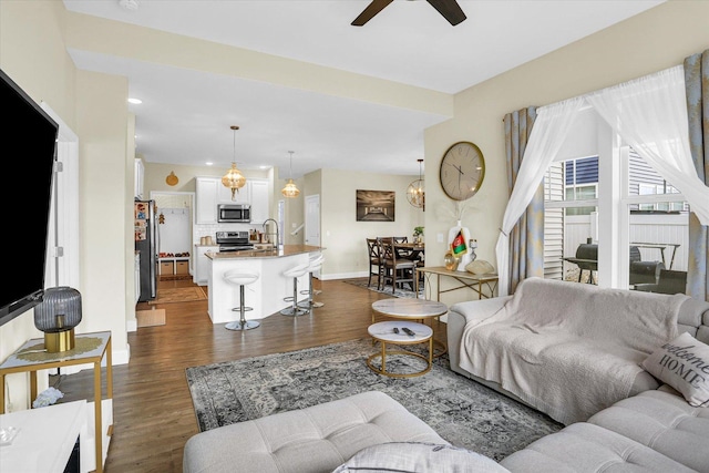 living room featuring ceiling fan, dark hardwood / wood-style flooring, and sink