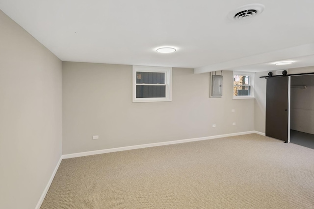 basement featuring light carpet, a barn door, and electric panel