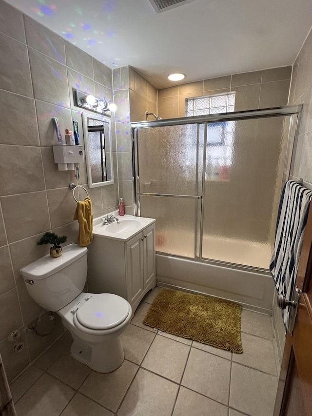 full bathroom with enclosed tub / shower combo, tile patterned floors, toilet, vanity, and tile walls