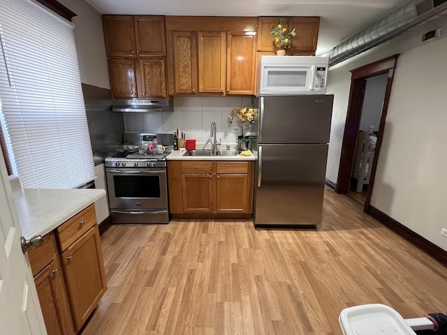 kitchen featuring backsplash, stainless steel appliances, light hardwood / wood-style floors, and sink