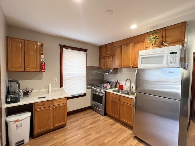 kitchen featuring appliances with stainless steel finishes, backsplash, light hardwood / wood-style floors, and sink