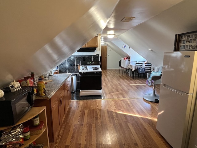 additional living space with wood-type flooring and vaulted ceiling