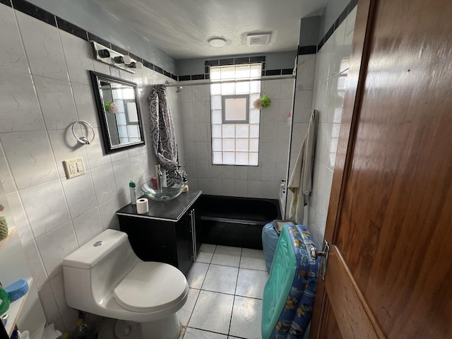 bathroom featuring tile patterned flooring, vanity, toilet, and tile walls