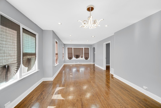 unfurnished living room with hardwood / wood-style flooring and an inviting chandelier