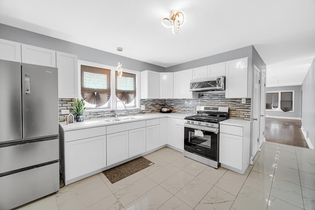 kitchen featuring white cabinets, decorative backsplash, sink, and appliances with stainless steel finishes