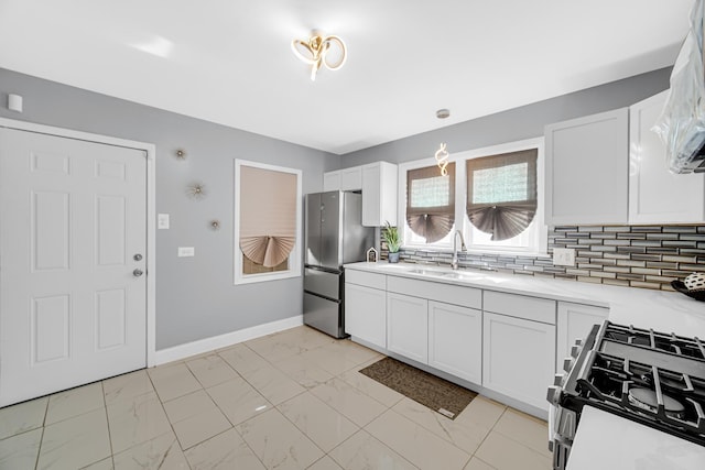 kitchen featuring stainless steel fridge, gas stove, white cabinetry, and sink