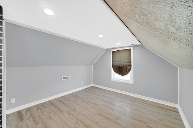 additional living space with light hardwood / wood-style floors and lofted ceiling