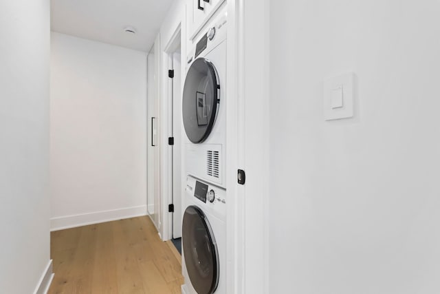 washroom with stacked washer / drying machine and light hardwood / wood-style floors