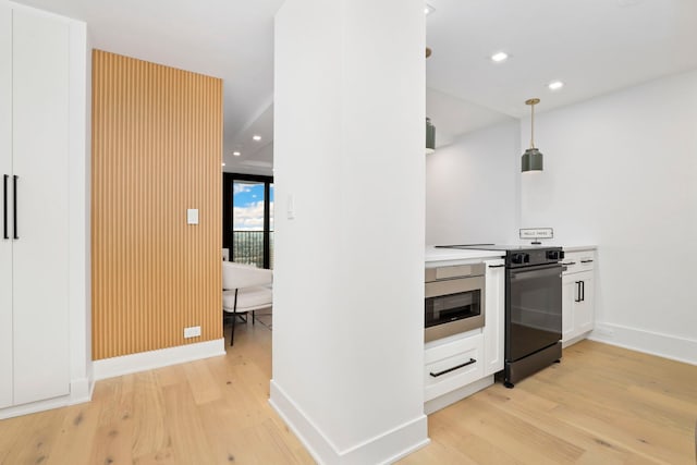 kitchen featuring white cabinetry, light hardwood / wood-style flooring, pendant lighting, and appliances with stainless steel finishes