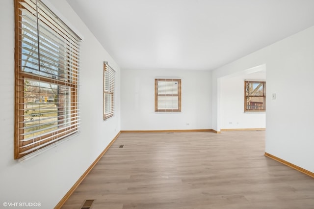 empty room with a wealth of natural light and light hardwood / wood-style flooring