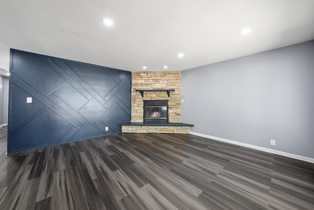 unfurnished living room featuring a stone fireplace and dark wood-type flooring