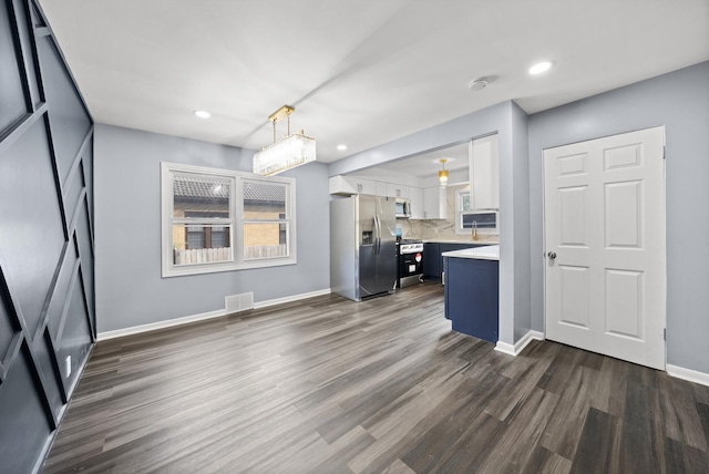 kitchen with white cabinetry, dark wood-type flooring, stainless steel appliances, tasteful backsplash, and decorative light fixtures