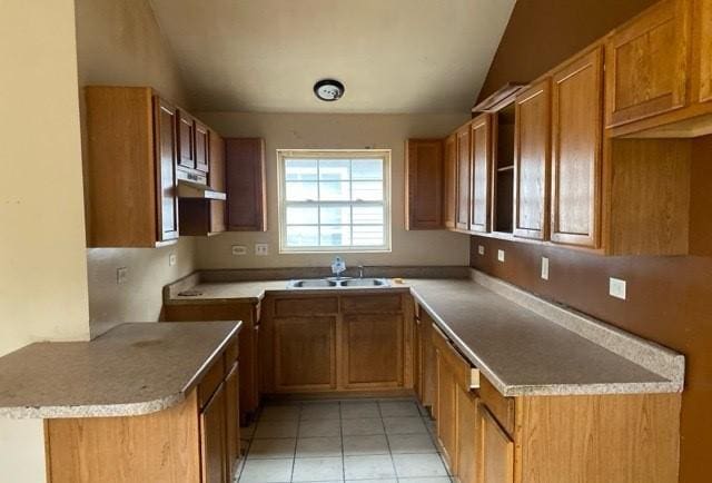 kitchen with lofted ceiling, light tile patterned flooring, kitchen peninsula, and sink