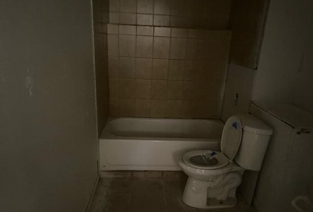 bathroom with tile patterned floors, tiled shower / bath, and toilet