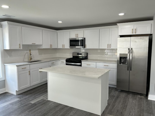 kitchen featuring sink, stainless steel appliances, dark hardwood / wood-style flooring, decorative backsplash, and white cabinets