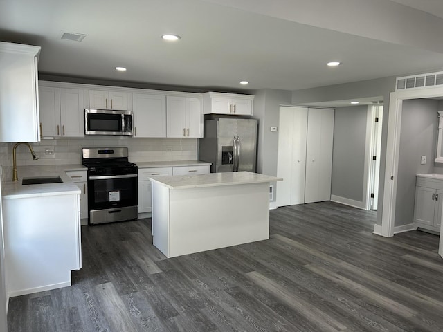 kitchen featuring white cabinets, sink, decorative backsplash, a kitchen island, and stainless steel appliances