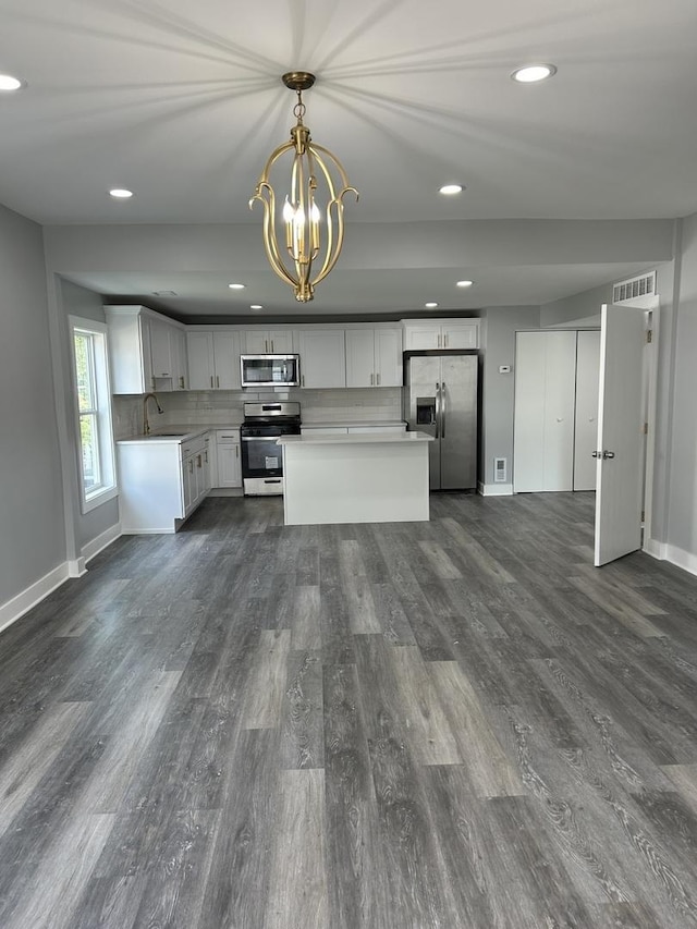 kitchen featuring appliances with stainless steel finishes, dark hardwood / wood-style flooring, a chandelier, white cabinetry, and hanging light fixtures