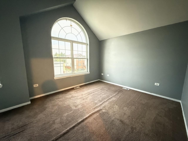 unfurnished room with dark carpet and lofted ceiling