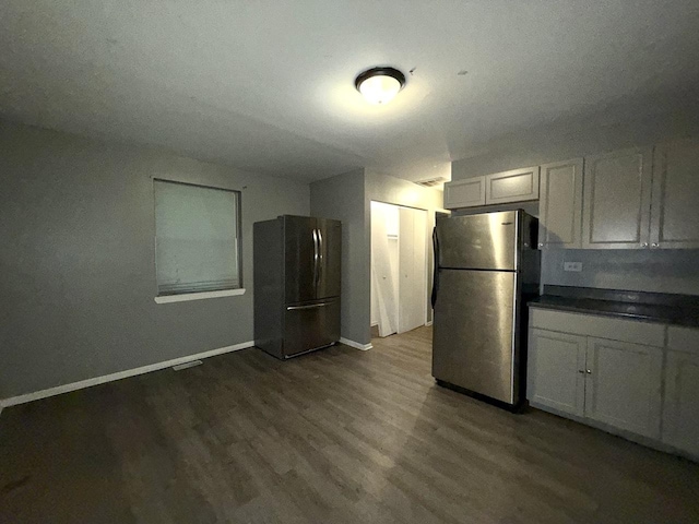 kitchen with white cabinets, dark hardwood / wood-style floors, and stainless steel refrigerator