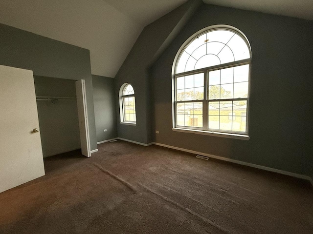 unfurnished bedroom featuring dark carpet, a closet, and vaulted ceiling