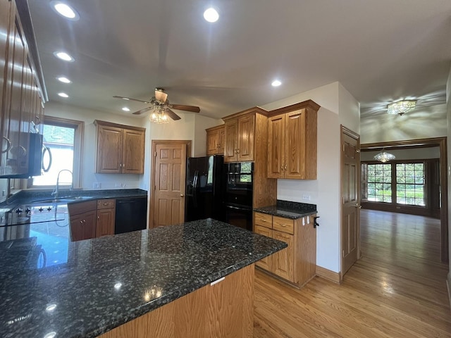 kitchen with kitchen peninsula, ceiling fan, sink, black appliances, and light hardwood / wood-style flooring