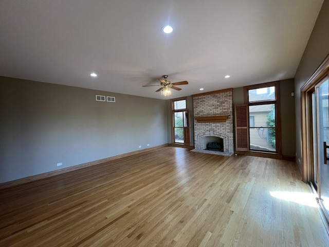 unfurnished living room with a fireplace, ceiling fan, and light hardwood / wood-style flooring