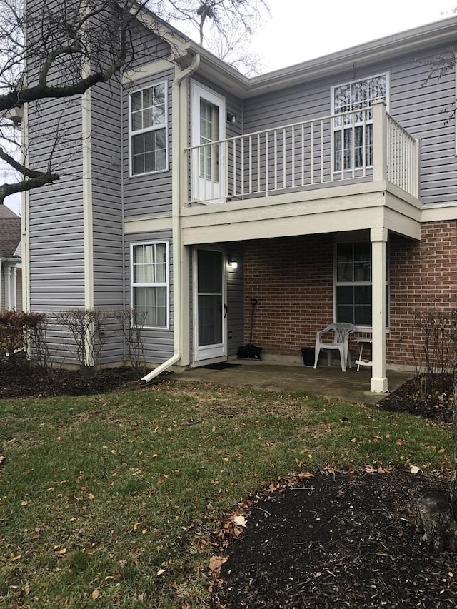 back of property featuring a yard, a balcony, and a patio