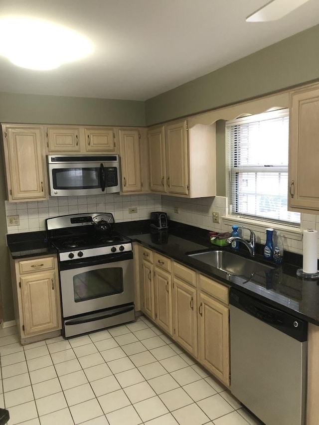 kitchen featuring decorative backsplash, light brown cabinetry, sink, and appliances with stainless steel finishes