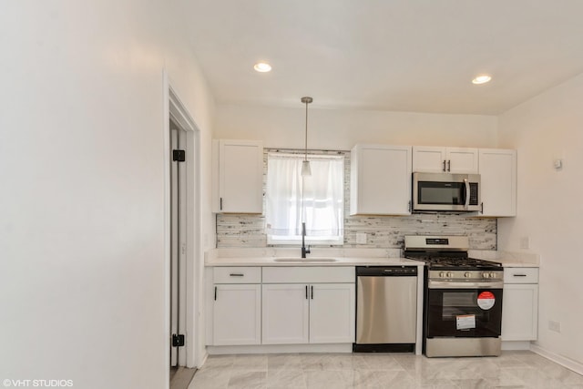 kitchen with stainless steel appliances, sink, white cabinets, tasteful backsplash, and pendant lighting