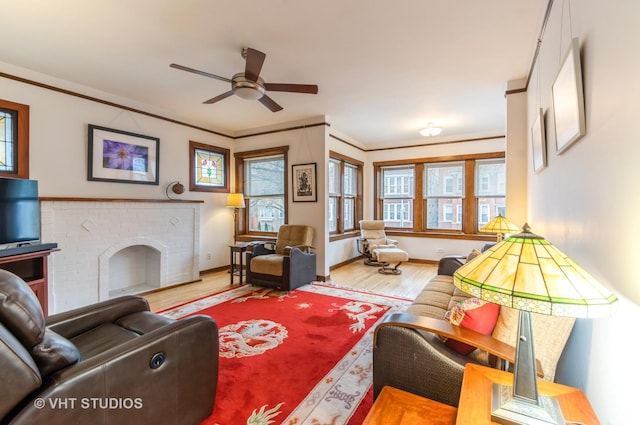 living area featuring ceiling fan, a fireplace, wood finished floors, baseboards, and ornamental molding