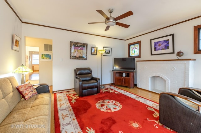 living area with ornamental molding, a brick fireplace, visible vents, and a ceiling fan