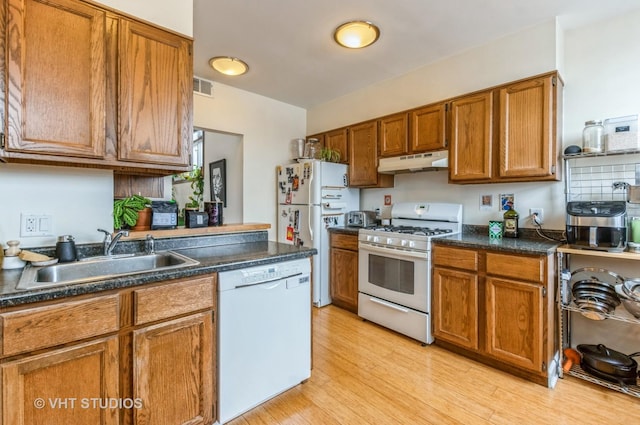 kitchen featuring visible vents, brown cabinetry, a sink, white appliances, and under cabinet range hood