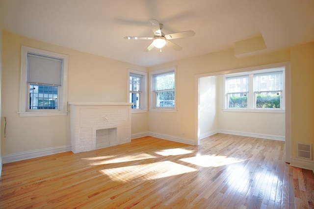 unfurnished living room featuring baseboards, visible vents, ceiling fan, hardwood / wood-style floors, and a fireplace