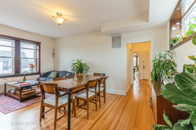 dining area featuring light wood-style flooring, visible vents, and baseboards