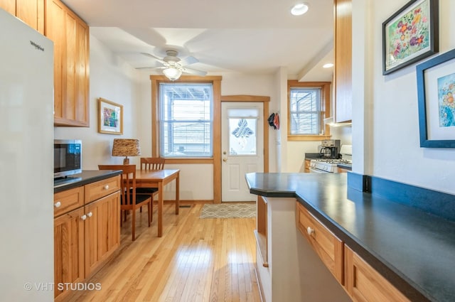 kitchen with light wood finished floors, dark countertops, recessed lighting, white appliances, and baseboards