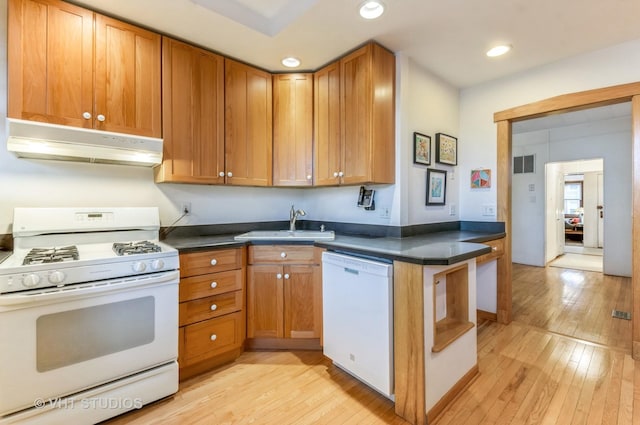 kitchen featuring dark countertops, visible vents, a sink, white appliances, and under cabinet range hood