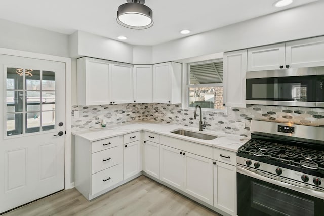 kitchen featuring white cabinets, sink, decorative backsplash, light stone countertops, and appliances with stainless steel finishes