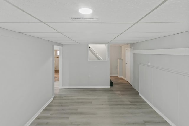 basement featuring a drop ceiling and hardwood / wood-style flooring