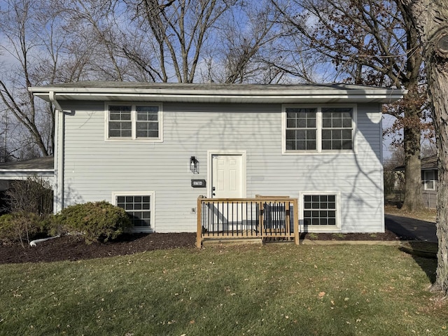 rear view of property featuring a lawn and a deck