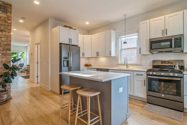 kitchen with appliances with stainless steel finishes, sink, a center island, white cabinetry, and a breakfast bar area